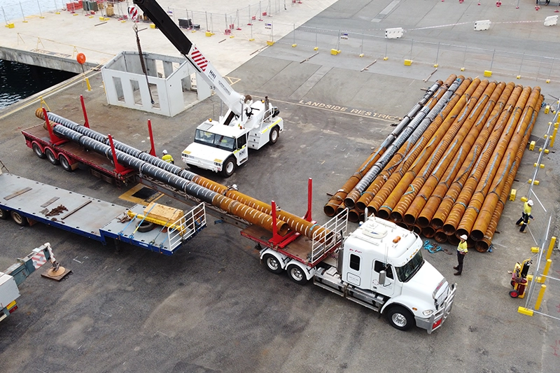Crane truck delivering large pipes